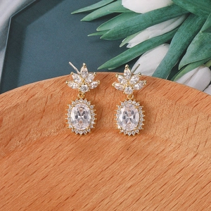 Detalle de pendientes dorados de lujo con loto de circón y piedras ovales brillantes