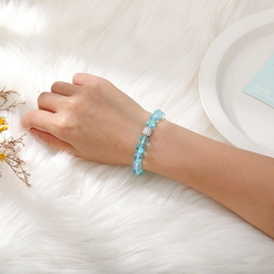 Detail of beaded stretch bracelet with light blue frosted beads and silver crystal charm