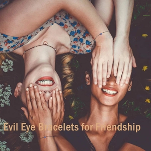 Detail showing two friends wearing evil eye friendship bracelets and a heart necklace on grass