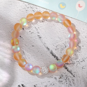 Detail of matte iridescent moonstone beads and silver crystal charm on elastic bracelet