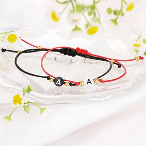 Dettaglio di braccialetti regolabili in corda intrecciata rossa e nera con charm lettera A