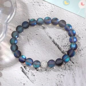 Frosted moonstone stretch bracelet with sparkling pave crystal ball on white stone surface
