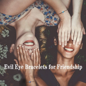 Two women on grass wearing minimalist black string evil eye friendship bracelets