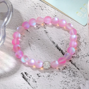 Macro detail of pink frosted mermaid bead bracelet with a crystal pave metal centerpiece