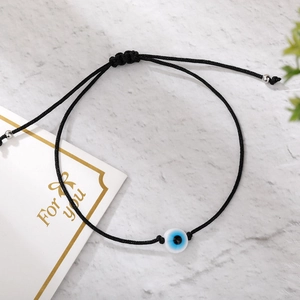 Detail of adjustable black woven rope evil eye bracelet with silver metallic beads