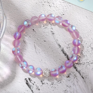 Detailed shot of purple iridescent beaded bracelet with a silver crystal pavé ball charm
