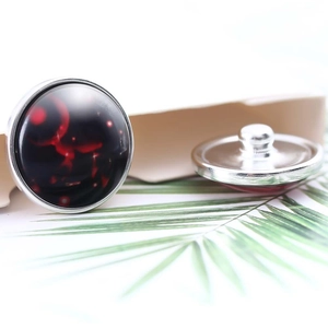 Macro detail of 20mm glass cabochon button with abstract black and red pattern