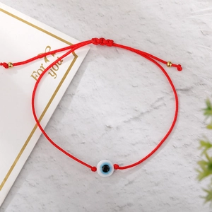 Detail of red braided Evil Eye bracelet with adjustable golden beads and gift card