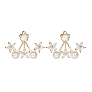 Detalle de pendientes dorados con flores de circón y perlas blancas de gran brillo