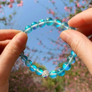 Elastic frosted moonstone beaded bracelet with silver rhinestone ball in outdoor setting