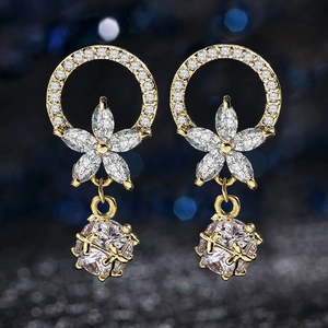 Primer plano de pendientes dorados con flores de circón y brillantes piedras redondas
