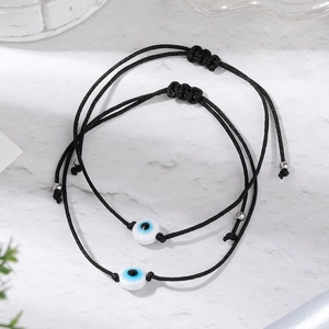 Close-up of adjustable evil eye braided bracelets with blue beads on marble background