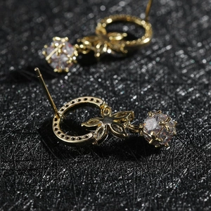 Detalle de pendientes de flor dorada con un gran cristal de corte cuadrado colgante