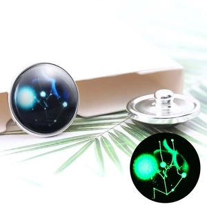 Macro detail of 20mm glow-in-the-dark zodiac snap button with starry constellation