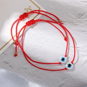 Close-up of two red woven Evil Eye bracelets with adjustable gold bead pull-string closures