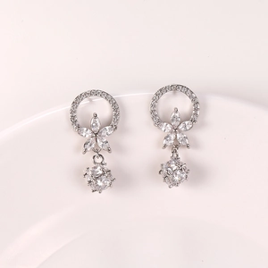 Detalle de pendientes plateados con flores de circón y gran gema tallada facetada