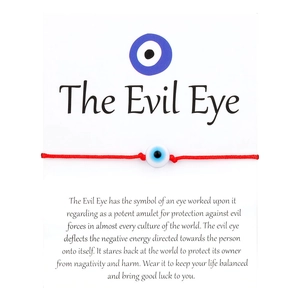 Macro shot of handcrafted red braided rope Evil Eye bracelet with protective card