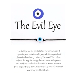 Detail of woven black string bracelet with Evil Eye bead on a white display card