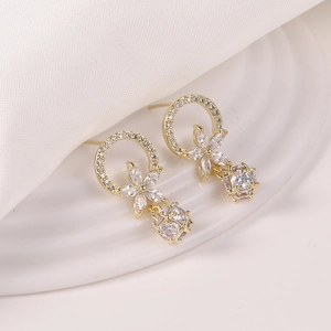Detalle de pendientes florales dorados con colgantes esféricos huecos con circonitas