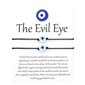 Detail of two black woven Evil Eye bracelets on a white card with descriptive text