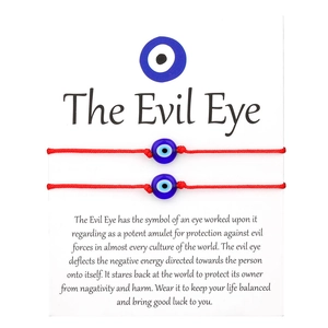 Handmade red woven Evil Eye protection bracelets on a white card with meaningful text