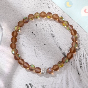 Macro shot of matte brown beaded stretch bracelet with shimmering blue-green luster and crystal ball