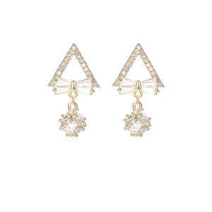 Detalle de pendientes dorados con lazo de cristal y esferas pavé brillantes colgantes