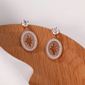 Detalle de pendientes de oro rosa con pavé de circonitas y diseño de patrón de estrella