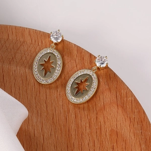 Detalle de pendientes dorados con pavé de circonitas y diseño de estrella calada