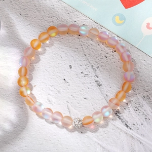 Iridescent beaded bracelet with a sparkling silver pavé ball on a stone background