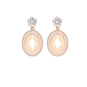 Detalle de pendientes ovalados en oro rosa con estrella de ocho puntas y circonitas cúbicas