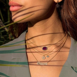 Detailed view of layered gold necklaces with Sagittarius symbol and Gemini pendant
