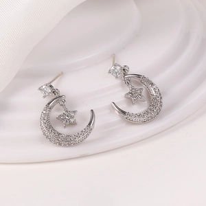 Primer plano de pendientes de plata con diseño de luna y estrella y circonitas brillantes