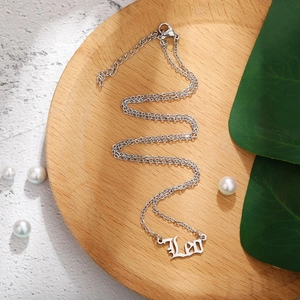 Macro shot of silver Leo zodiac necklace with gothic font on a wooden board with pearls