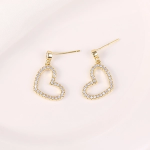 Detalle de pendientes de corazón dorados con borde de circonitas brillantes pavé