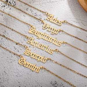 Close-up of golden stainless steel zodiac name necklaces in Gothic font with cross chains