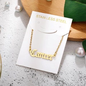 Macro detail of a gold stainless steel Cancer zodiac pendant necklace on a natural display