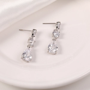 Detalle de pendientes colgantes plateados con circonitas sobre un plato blanco