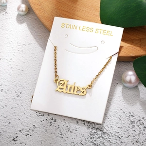 Detail of Aries gold stainless steel necklace on white card with decorative background