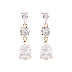 Detalle de pendientes dorados con circonitas blancas en forma de gota y corte redondo