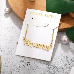 Detailed view of Aquarius zodiac necklace in gold finish on a white jewelry card
