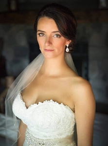 Detalle de vestido de novia de encaje blanco con pendientes de gota de circonita en modelo