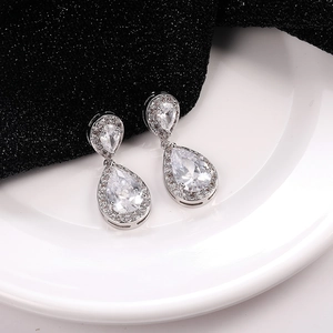 Detalle de pendientes de gota plateados con circonitas sobre fondo de alto contraste