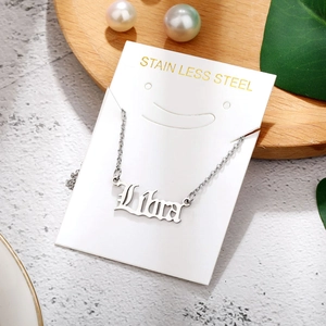 Macro view of the silver stainless steel Libra zodiac pendant on a white display card
