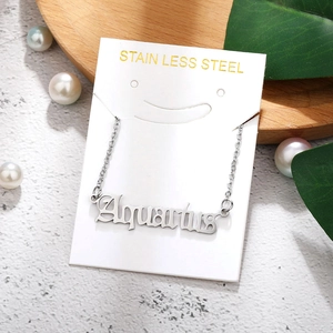 Macro shot of silver Aquarius zodiac pendant on a stainless steel card with pearls