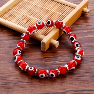 Close-up of red evil eye beaded bracelet with silver spacers on a bamboo tray