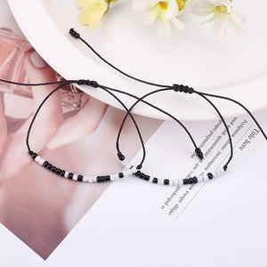 Detail of Morse code woven bracelets with black and white beads on waxed cord