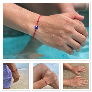 Wasserfestes rotes gewebtes Armband mit Nazar-Auge-Perle in einer Pool-Umgebung