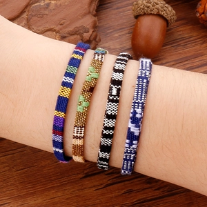 Detailopname van vier kleurrijke boheemse gevlochten armbanden met etnische geometrische motieven