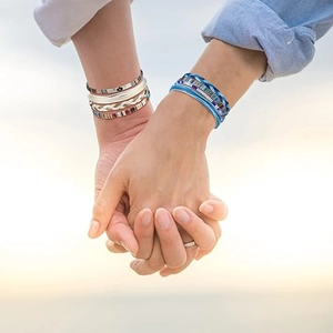 Detail van meerlagige boho geweven armbanden op handen in een natuurlijke buitenomgeving